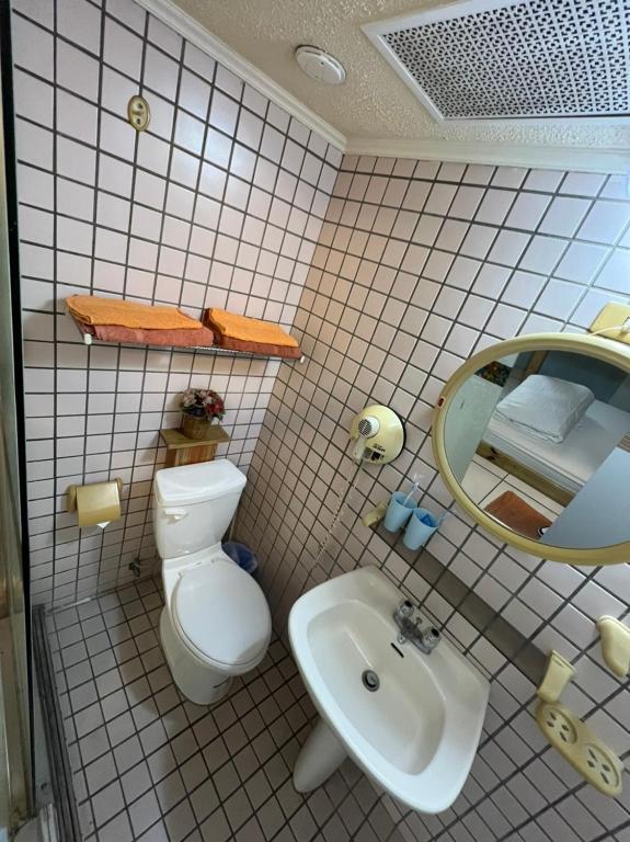 a bathroom with a toilet and a sink and a mirror at Boston Hotel in Chiayi City