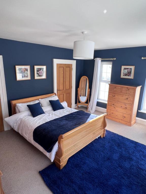 a bedroom with a large bed and a blue wall at Field View in Ashfield