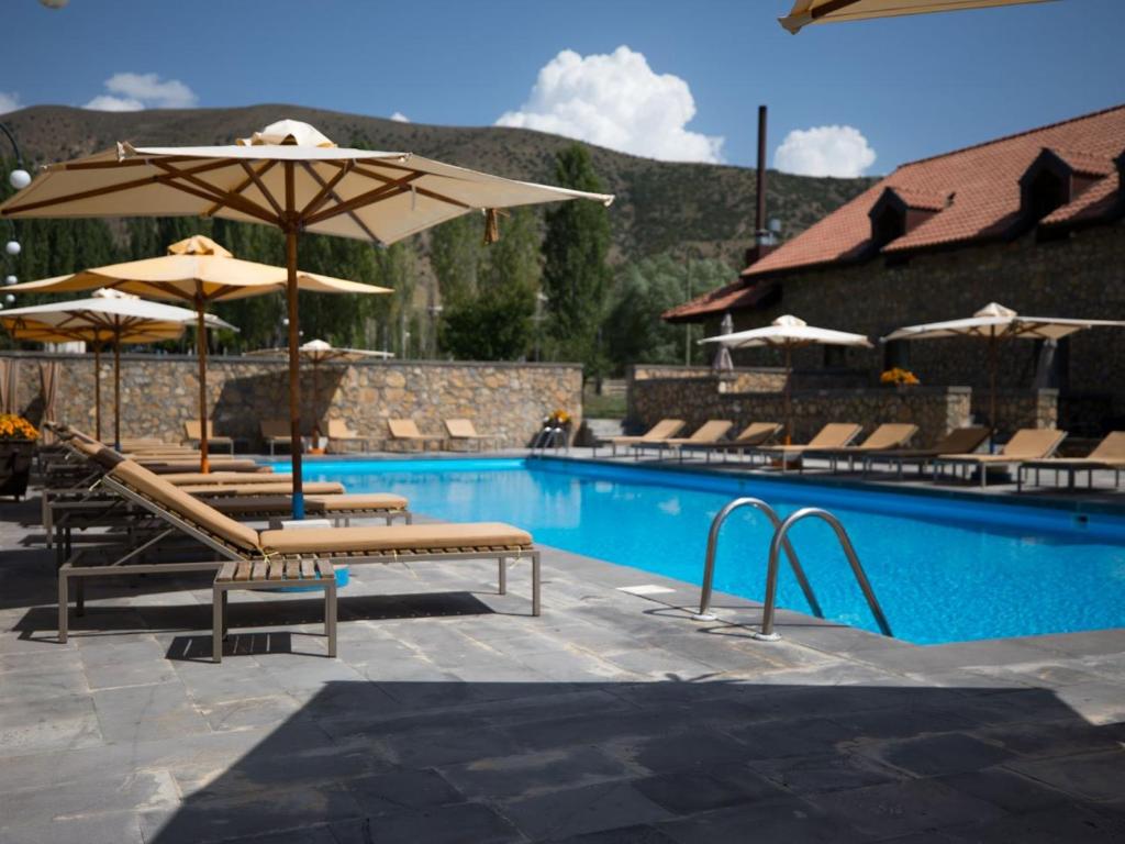uma piscina com cadeiras e guarda-sóis num resort em Tufenkian Avan Marak Tsapatagh Hotel em Kzylkʼend