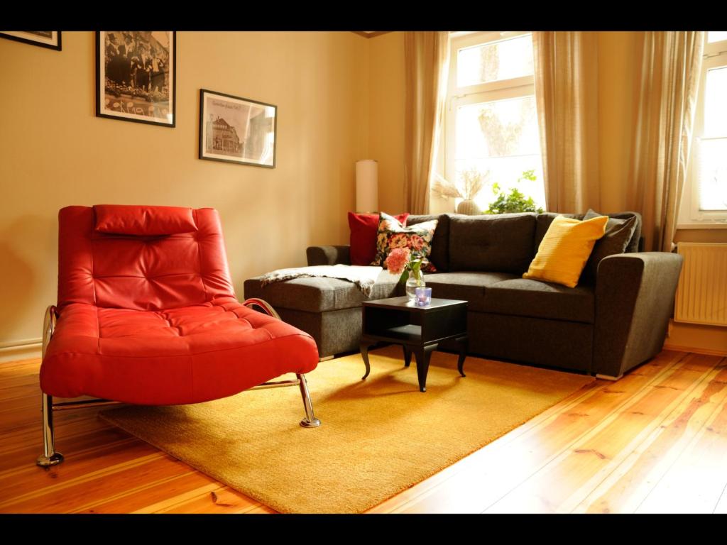 a living room with a red chair and a couch at NEU! Stilvolle FeWo Finsterwalde in Finsterwalde