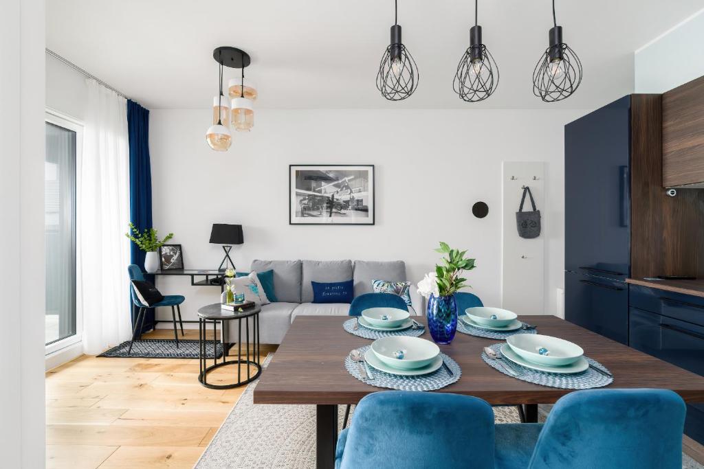 uma sala de estar com uma mesa de madeira e cadeiras azuis em 16th Floor Towarowa 39 City Center Avenida by Renters Prestige em Poznań