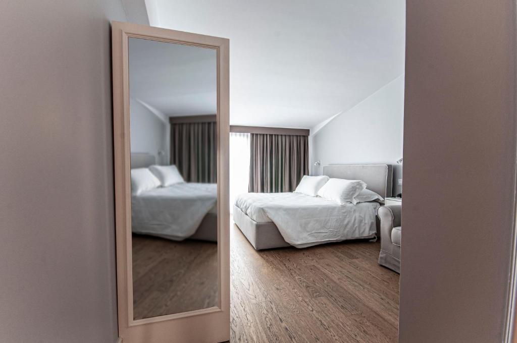 a mirror in a room with two beds and a couch at Spazio San Marco in Bergamo