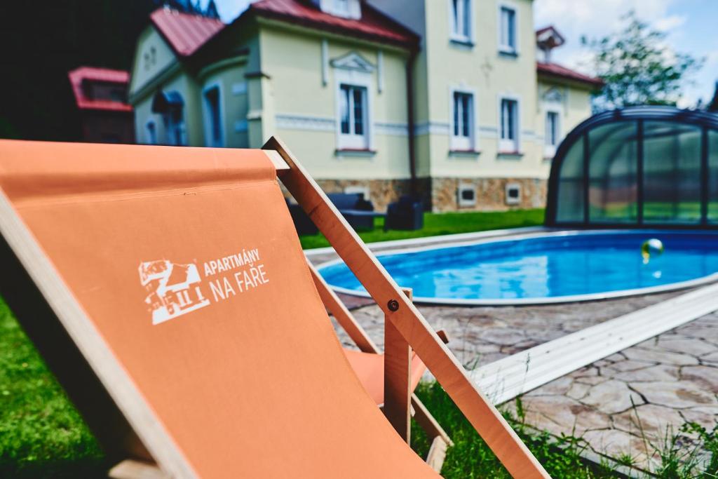 un panneau sur une chaise de jardin devant une maison dans l'établissement Apartmány Na Faře, à Bílá