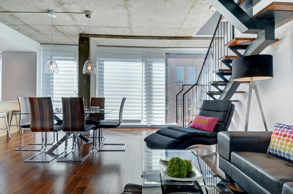 a living room with a staircase and a table and chairs at Les Immeubles Charlevoix - Le 760-506 in Quebec City