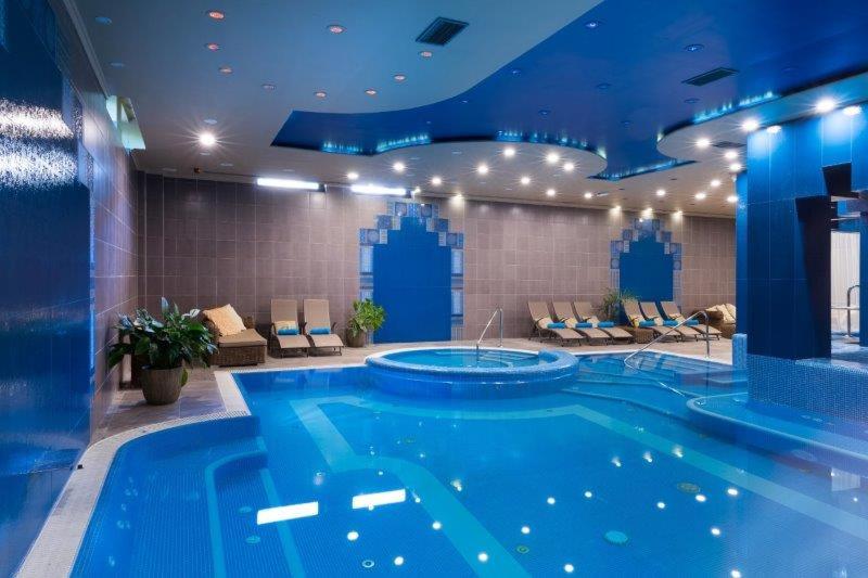 una gran piscina en una habitación de hotel con techo azul en Golden Ball Club, en Győr