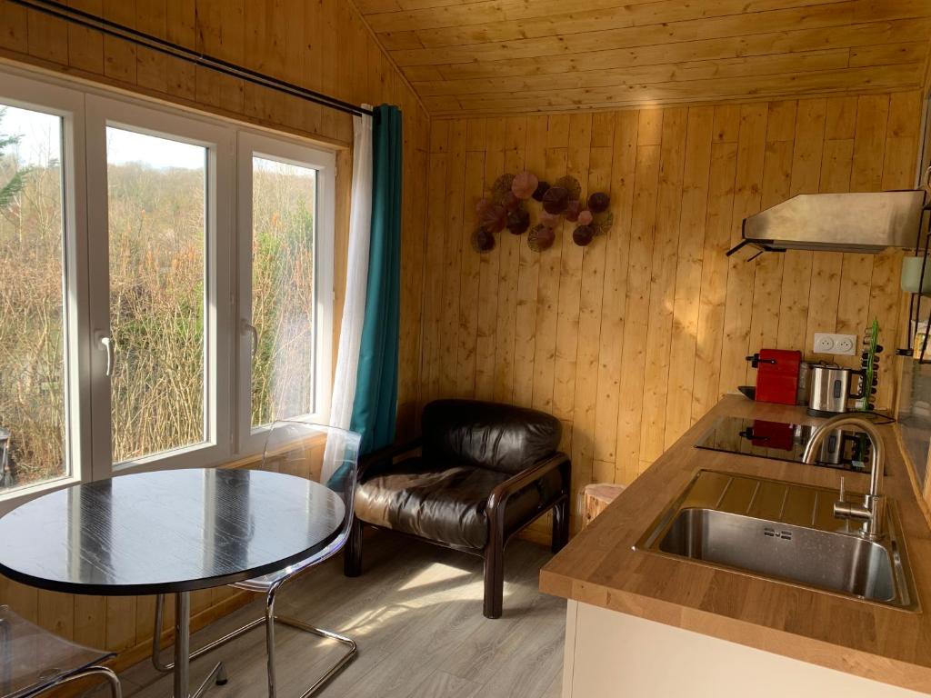 a kitchen with a sink and a table and a chair at chalet paradisiaque en bord de Marne Proche de Disneyland in Isles-lès-Villenoy