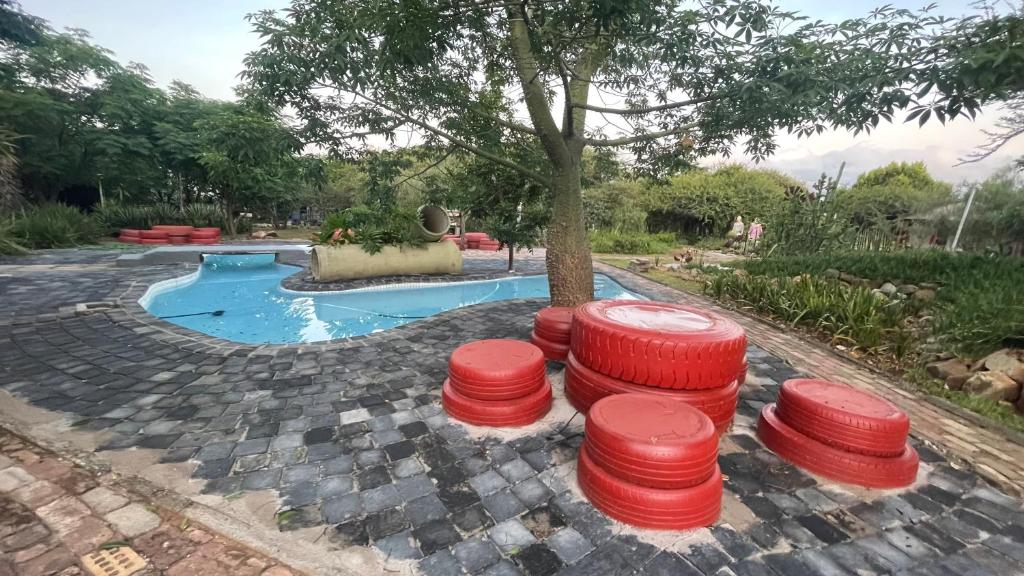 un grupo de taburetes rojos frente a una piscina en Klein Paradys Lodge - Polokwane, en Polokwane