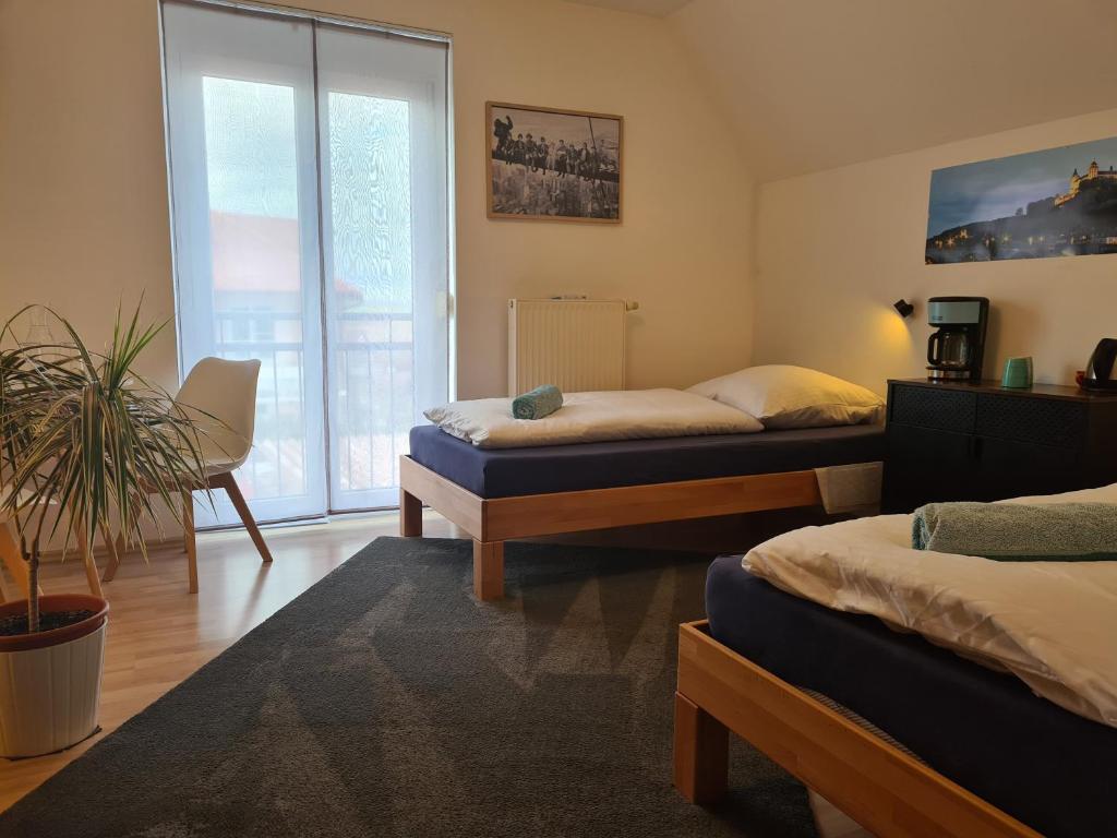 a bedroom with two beds and a potted plant at Lichtdurchflutetes Zimmer - Marienberg in Waldbüttelbrunn