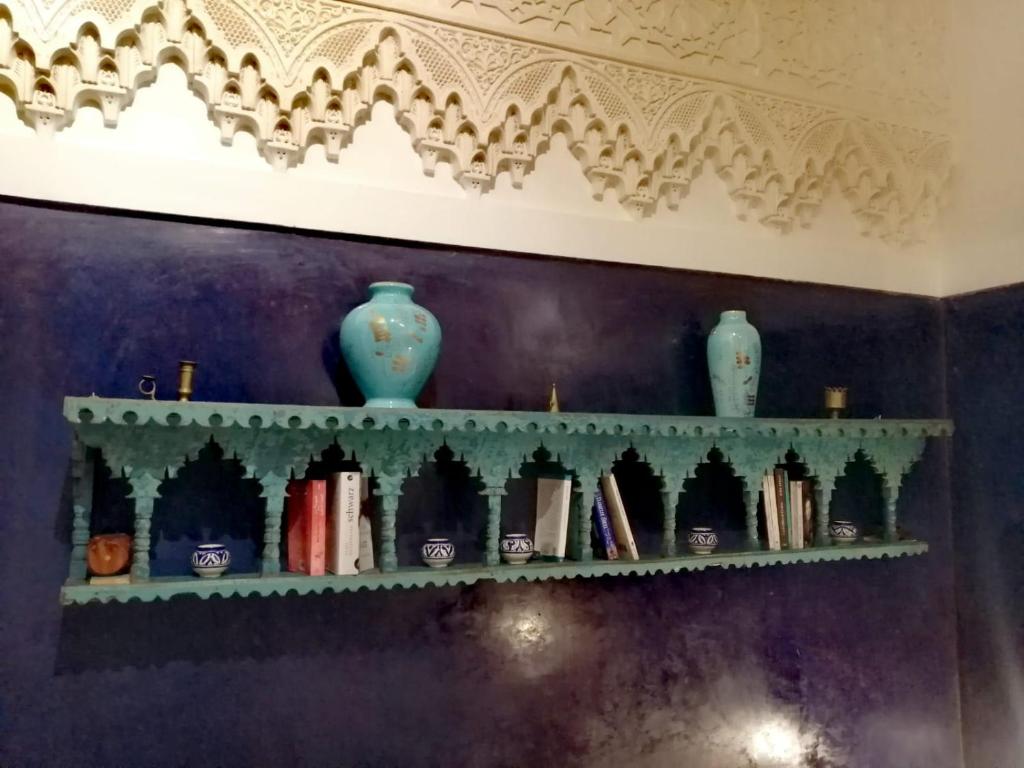 uma prateleira com livros e vasos numa parede em Les Bains de Fez Tara em Fez