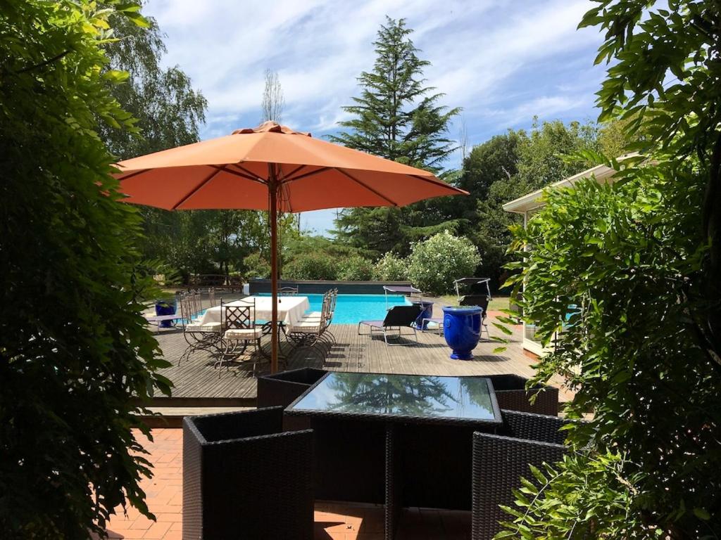 a table with an umbrella next to a pool at Villa charmante à Nalliers avec piscine in Nalliers