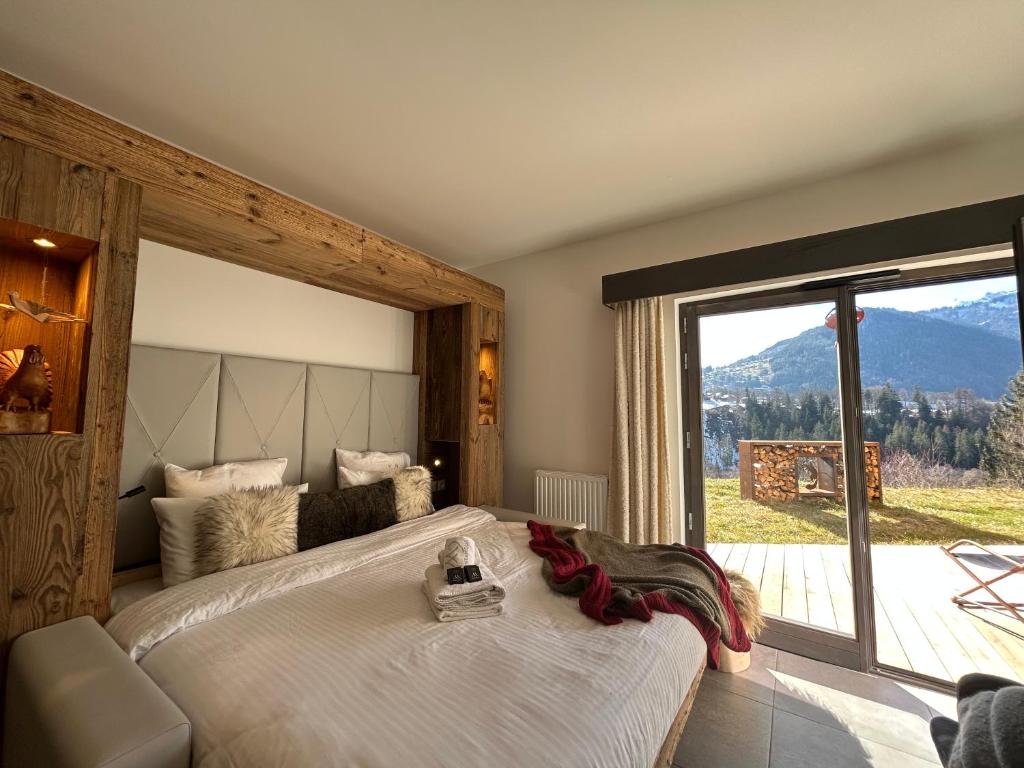 a bedroom with a large bed with a large window at Les Trois Chaufatons - Chalets Boutiques in Montriond
