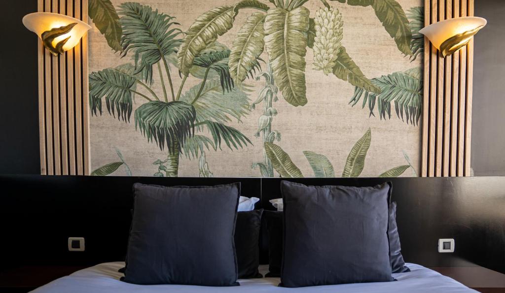 a bed with two pillows and a wall with a painting at Hôtel Gallia Cannes in Cannes