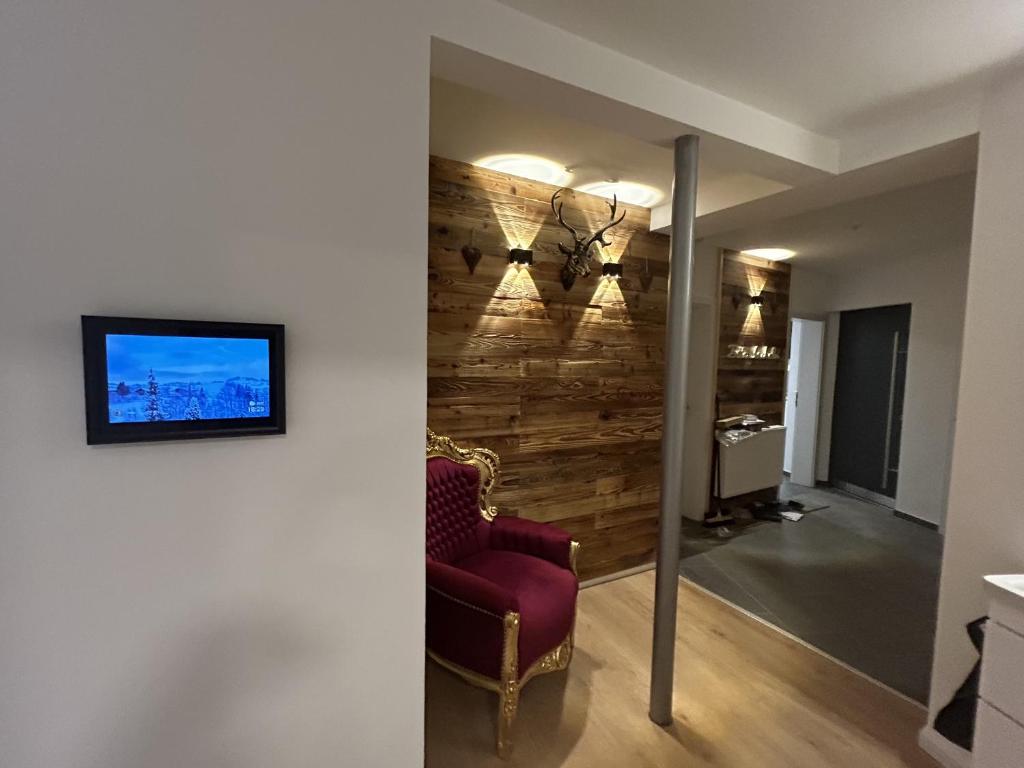 ein Wohnzimmer mit einem roten Stuhl und einem TV in der Unterkunft Aparthotel Waldhorn Wohnung Allgäustyle in Stuttgart