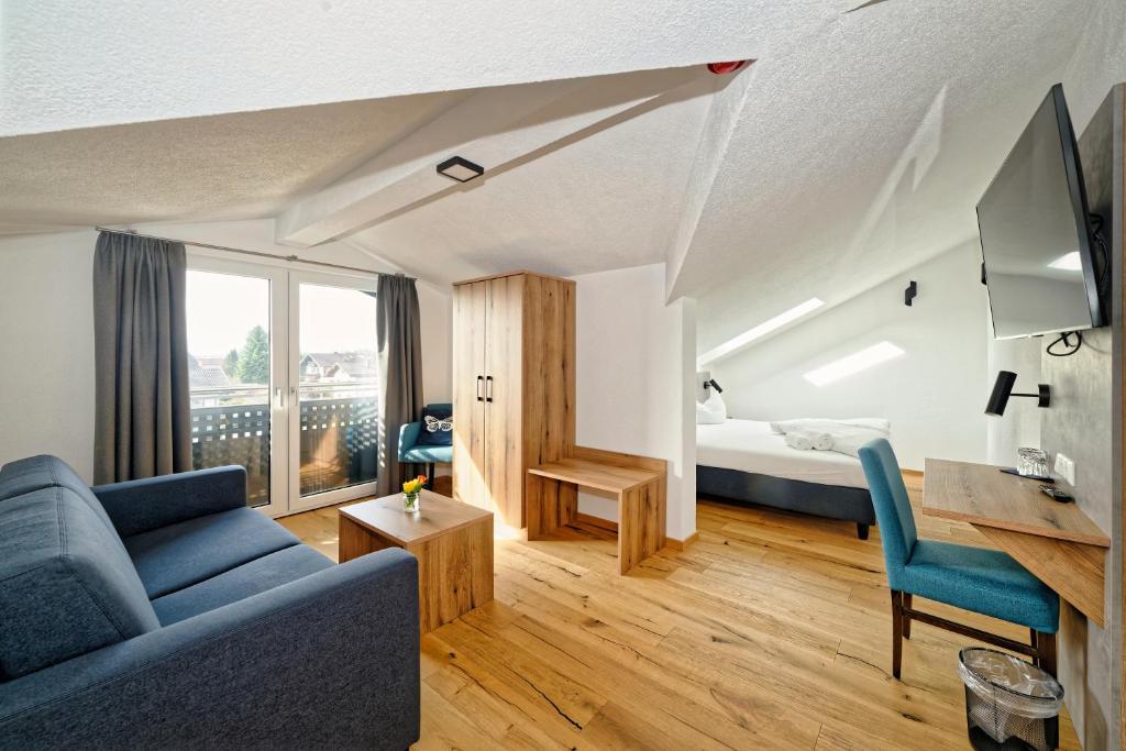 ein Wohnzimmer mit einem blauen Sofa und einem Bett in der Unterkunft Hotel 17 Seen in Eggstätt
