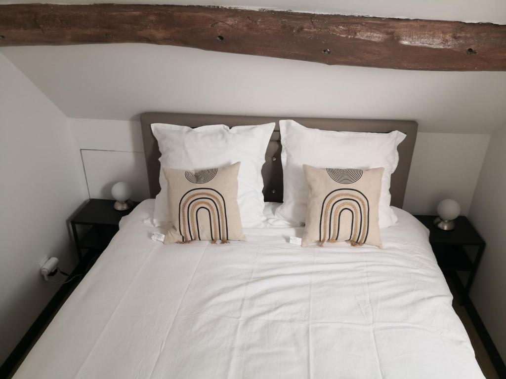 a bed with white sheets and pillows at petit logement Crecy la chapelle in Crécy-la-Chapelle
