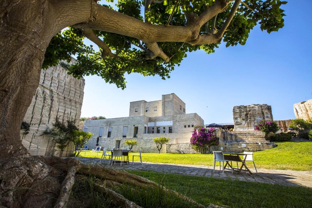 a view of a building with a tree in the foreground at Hotel Delle Cave in Favignana