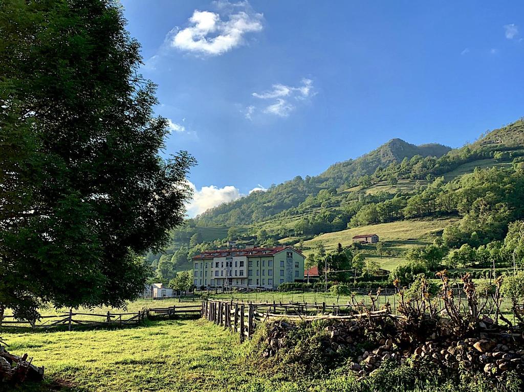 una casa en un campo con una valla y montañas en APARTAMENTO FELECHOSA, en Felechosa