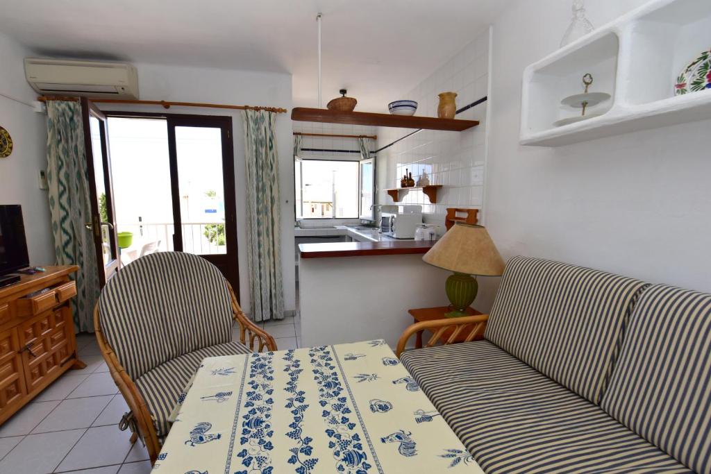 sala de estar con mesa y 2 sillas y cocina en Copacabana 27, en Es Pujols