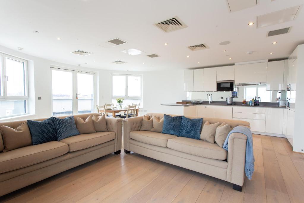 a living room with two couches and a kitchen at 2 Bed 2 Bath Penthouse With Amazing Views with Free Parking in London