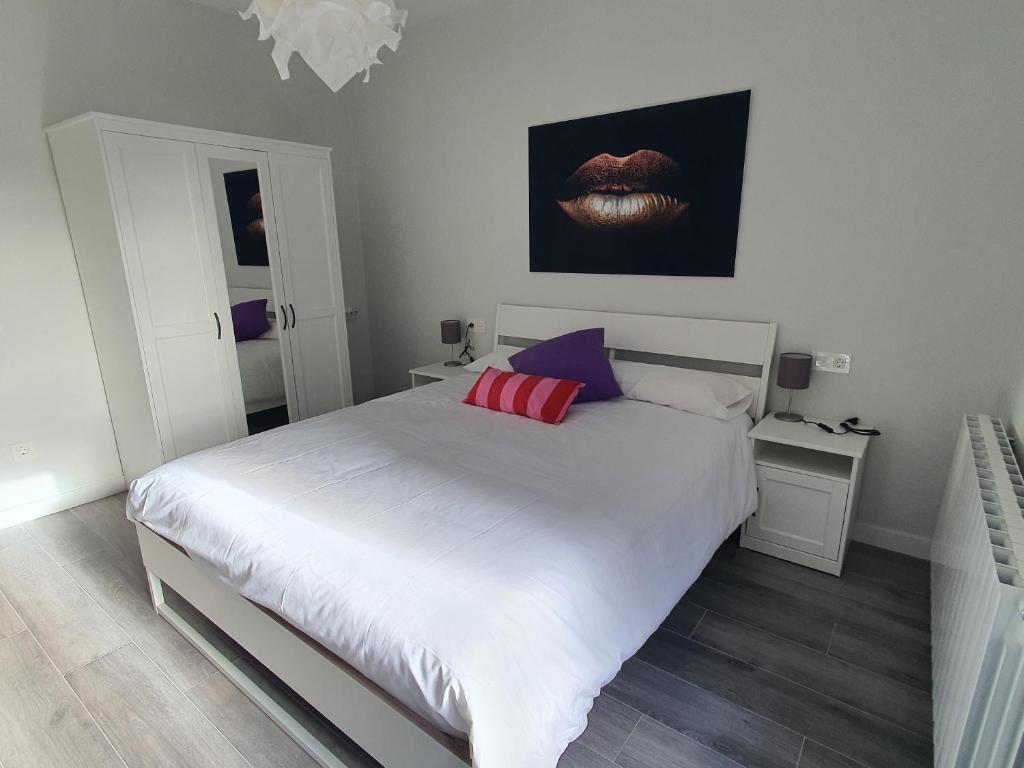una camera da letto con un letto bianco con cuscini rossi e viola di Casa albalunasss a Salamanca