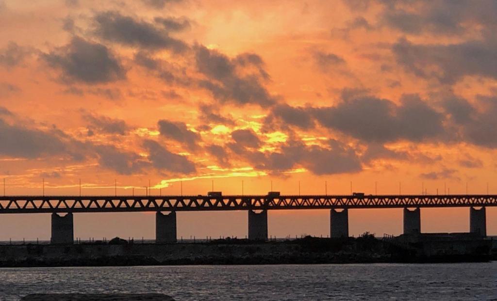 eine Brücke über das Wasser mit Sonnenuntergang im Hintergrund in der Unterkunft Lägenhet i Limhamn/sibbarp in Malmö