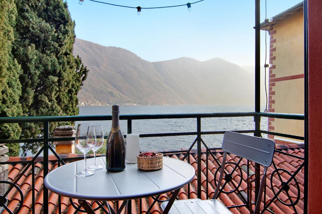 a table with a bottle and wine glasses on a balcony at Fogazzaro Lake View Apartment in Oria
