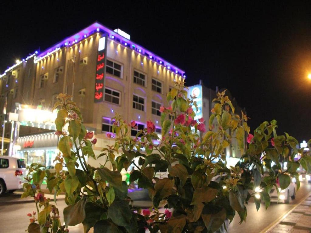 un edificio con luces moradas encima en نزل السلطان للأجنجة الفندقية, en Jazan