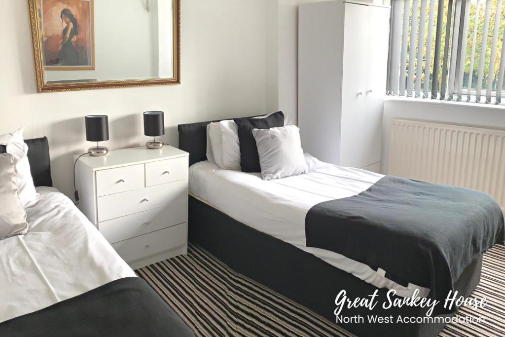 una camera con due letti e uno specchio di Great Sankey Serviced Accommodation a Warrington
