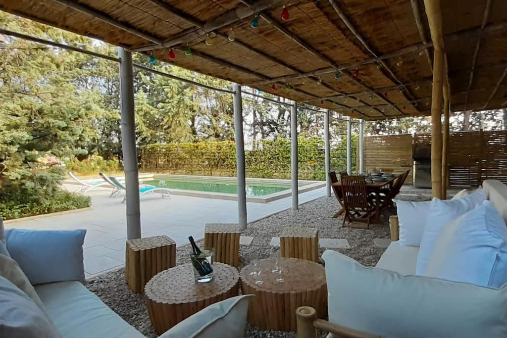 un patio con sofás, mesas y una piscina en Magnifique coin de mas avec piscine privative, en Meynes