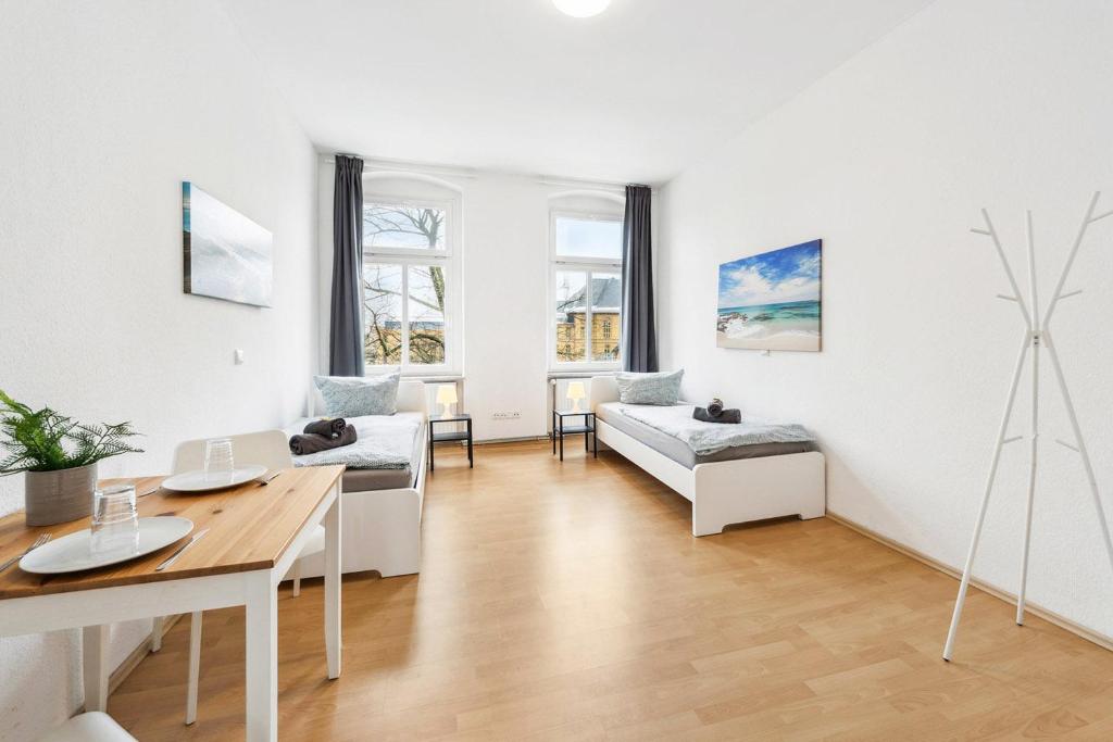 a white living room with a table and a couch at Gemütliche Apartments im Herzen von Halle in Halle an der Saale