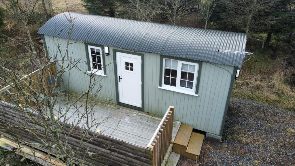 a green tiny house with a porch and a white door at Blair snug hut in Kelty