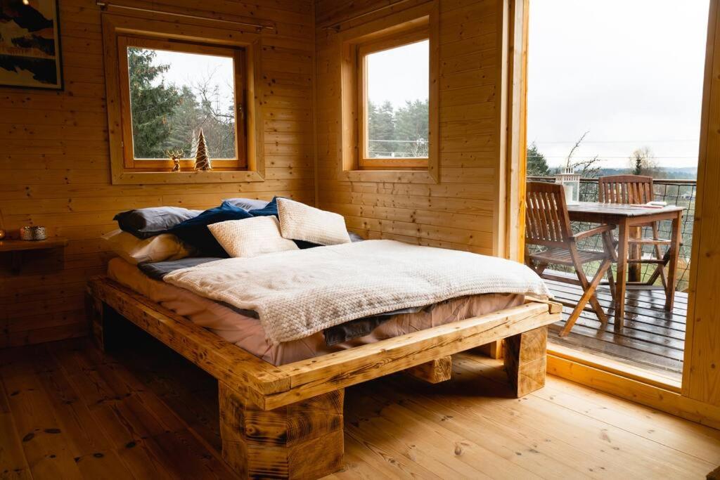a bed in a wooden room with a balcony at Tiny House nad Českým rájem in Všelibice