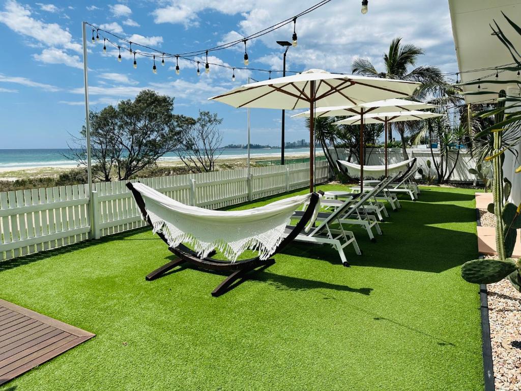 a hammock and chairs on a lawn near the beach at Tessa's on the Beach in Gold Coast