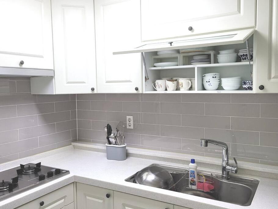 a kitchen with a sink and white cabinets at SinNaMu Family House in Suwon