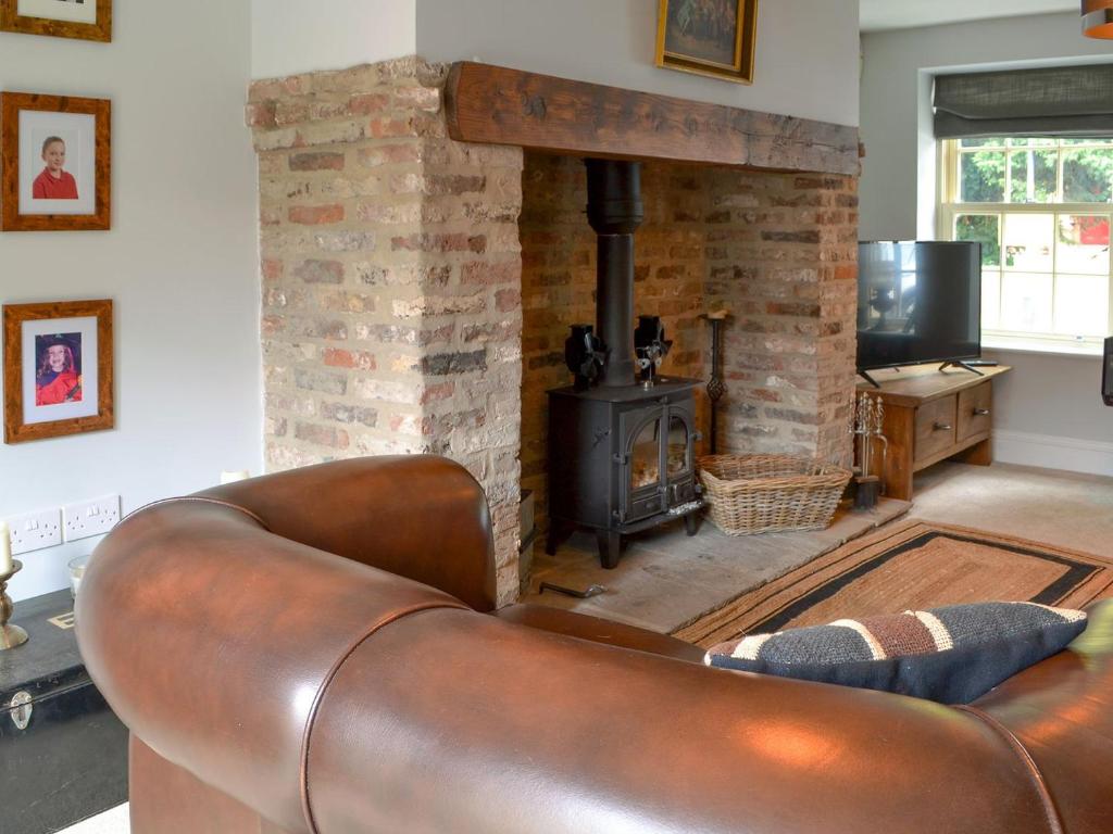 a leather couch in a living room with a fireplace at Loyal Cerise in Cawood