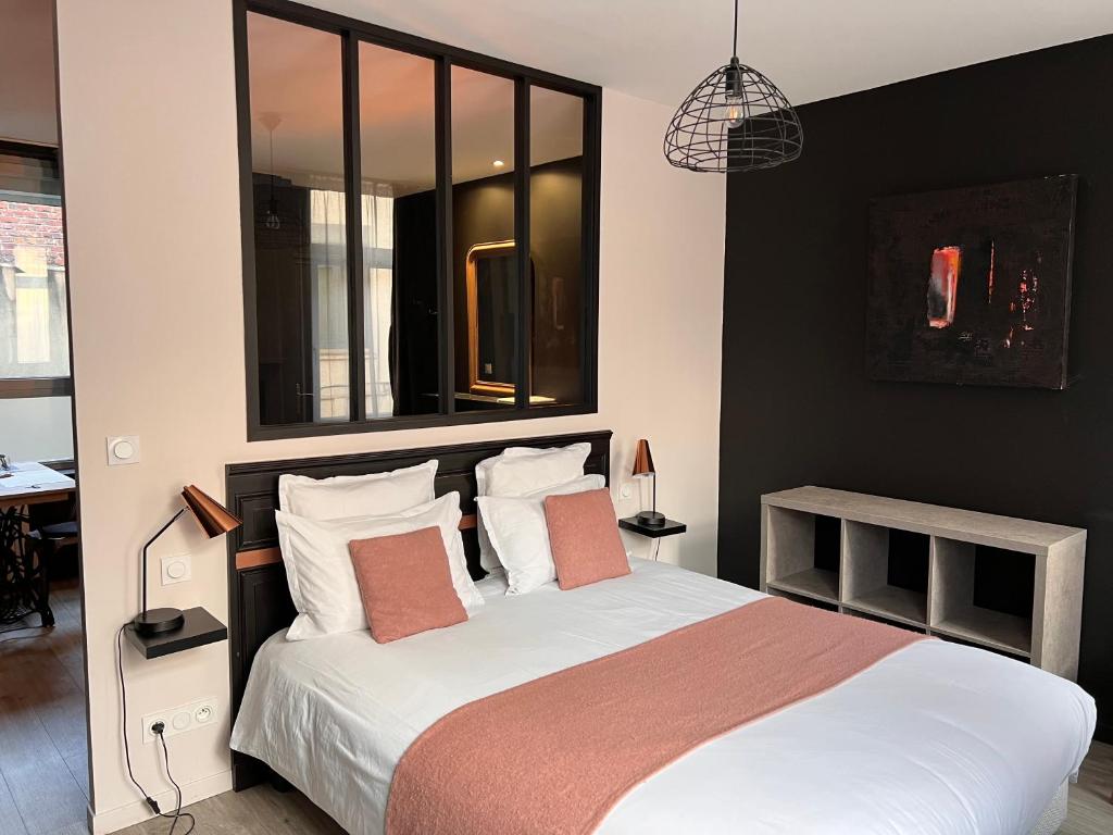 - une chambre avec un lit doté de draps blancs et d'oreillers orange dans l'établissement PlacesAppart, à Arras
