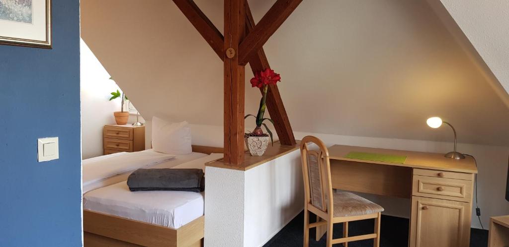 a bedroom with a bed and a desk with a chair at Zur Eiche - Pension in Böhlen