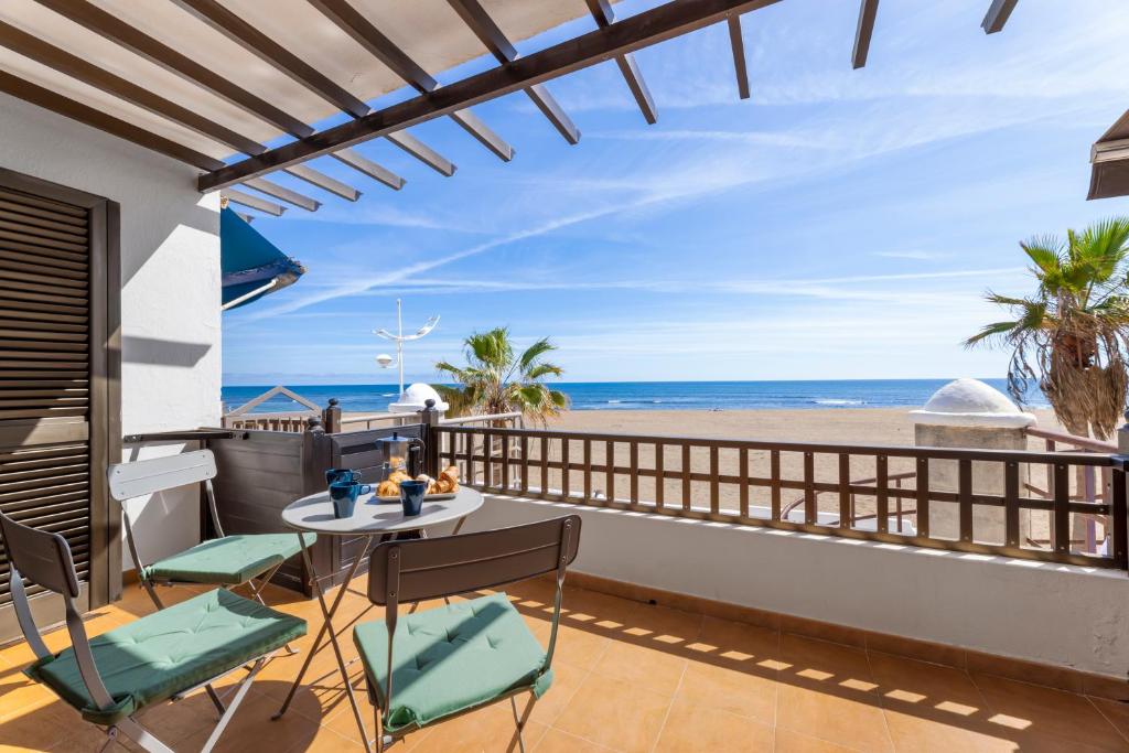 een balkon met een tafel en stoelen en uitzicht op het strand bij Home2Book Charming Seashell Apartment Beachview in Playa Honda
