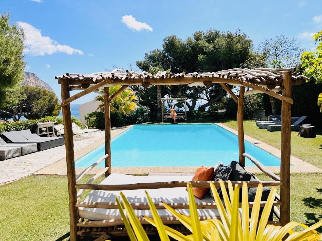 uma piscina com uma pérgula de madeira ao lado de uma piscina em Astoria Villa maison d hôtes Appartement vue mer avec piscine em Cassis