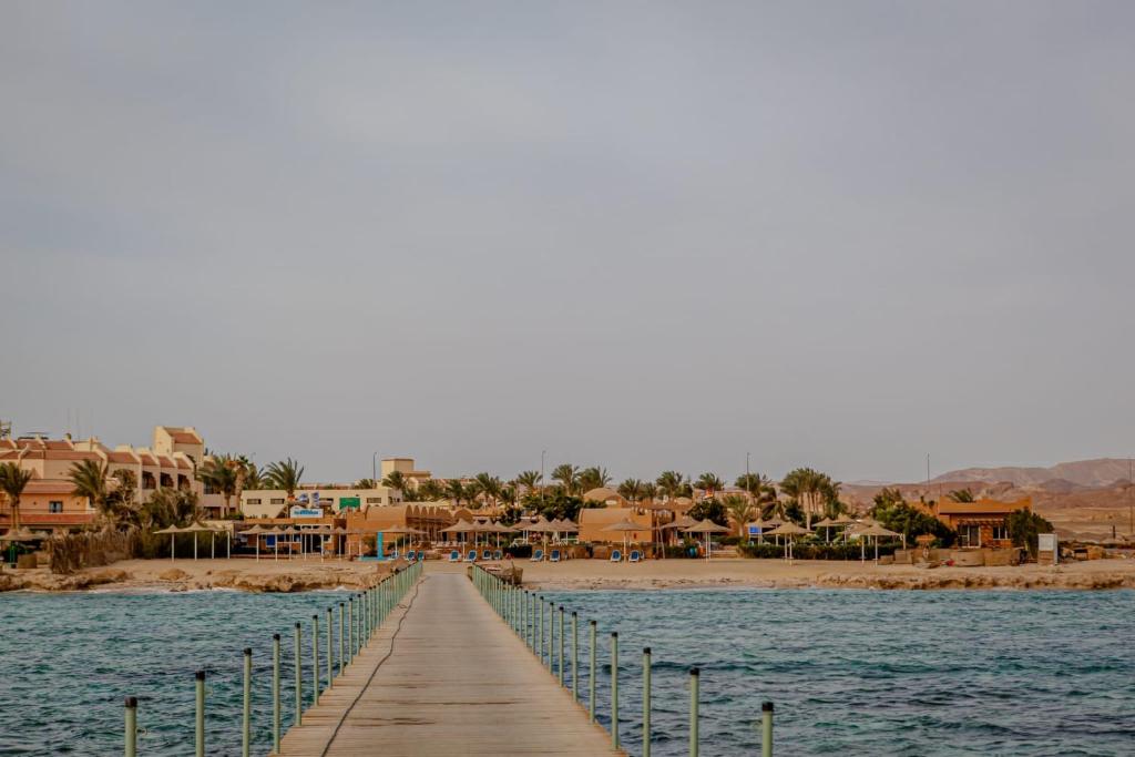 a wooden boardwalk leading to a beach with houses at Silver Beach Boutique Hotel in Quseir
