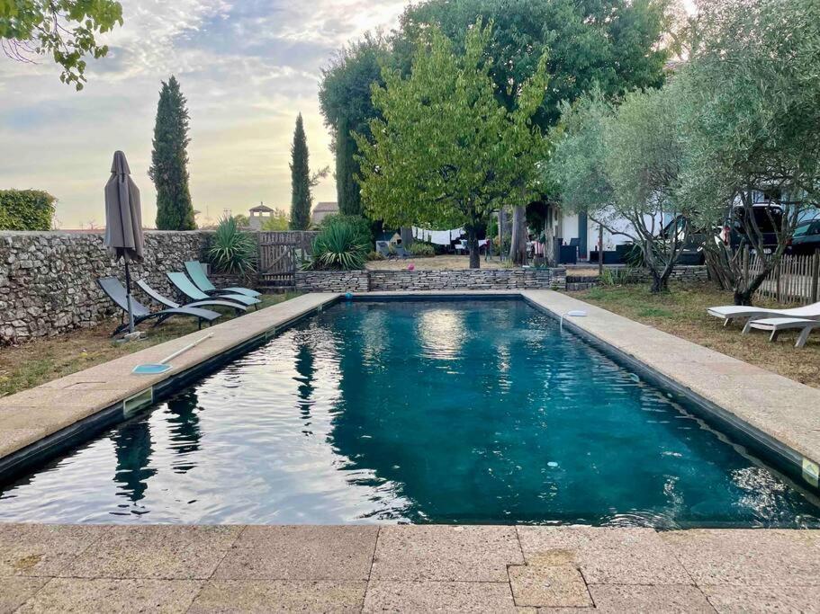 a swimming pool in a yard with chairs and trees at La maison du prieuré in Vézénobres
