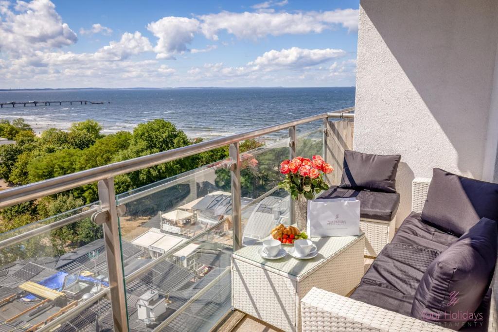 a balcony with a table with a laptop and a view of the ocean at Your Holidays Promenada Gwiazd 28 in Międzyzdroje