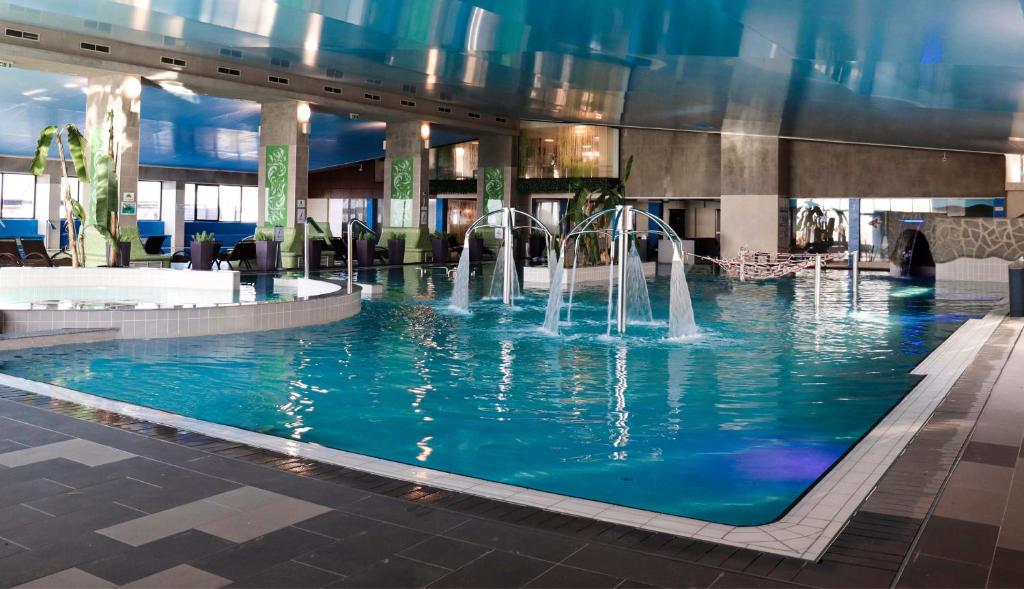 a swimming pool with water fountains in a building at Primera Dru Hotel&Spa in Baia Mare
