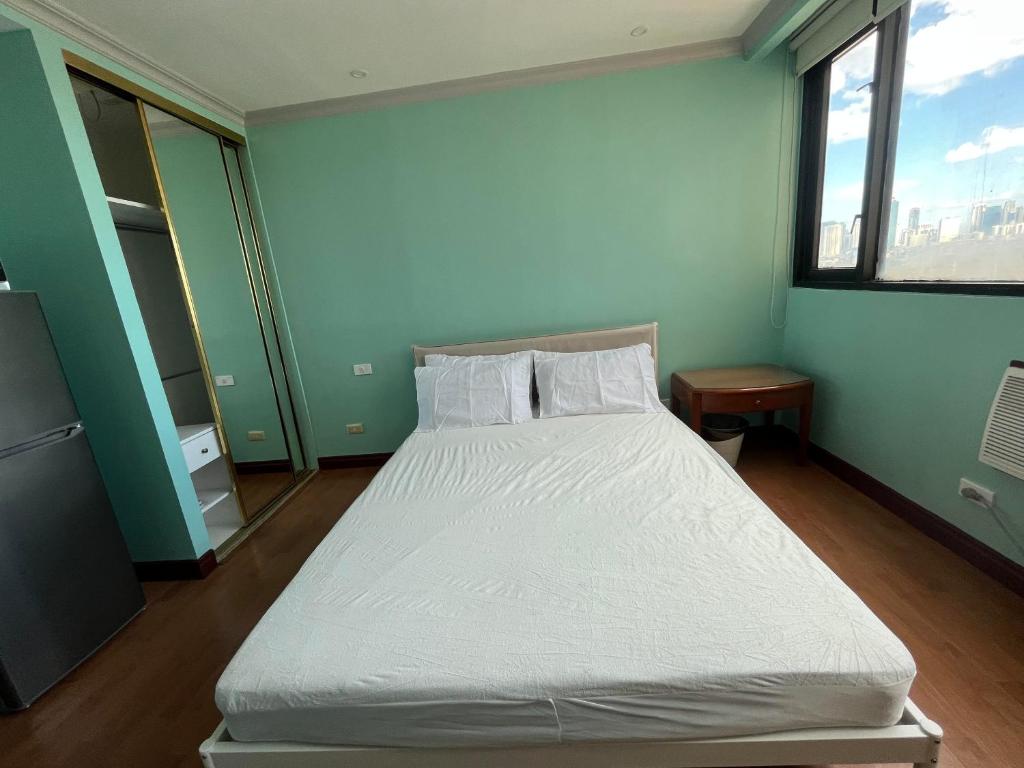 - une chambre avec un lit blanc dans une pièce verte dans l'établissement The Luxurious byTERBAIK, à Manille