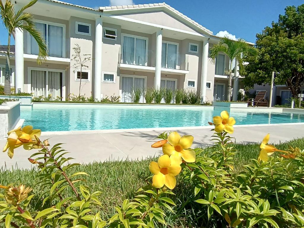 una casa con piscina y flores amarillas en 7 Heaven Arraial D'ajuda - SUA CASA EM ARRAIAL - Gileade, en Porto Seguro