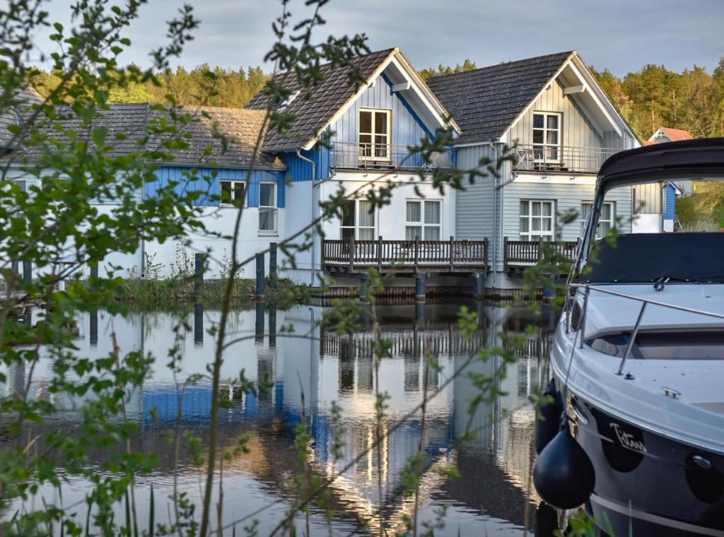 a house on the water with a boat in front at Precise Resort Marina Wolfsbruch - Familienapartments in Rheinsberg