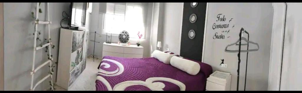 um quarto com uma cama roxa e uma janela em Habitación suite con baño a pies del río Guadalquivir em Coria del Río