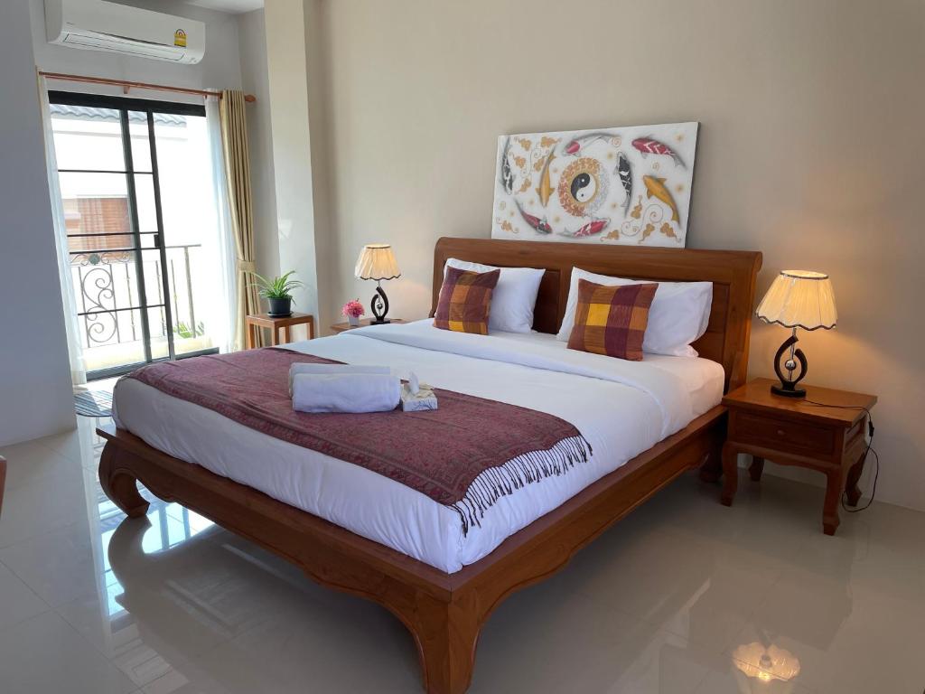a bedroom with a large bed with two lamps and a window at Laph Kham House in Chiang Mai