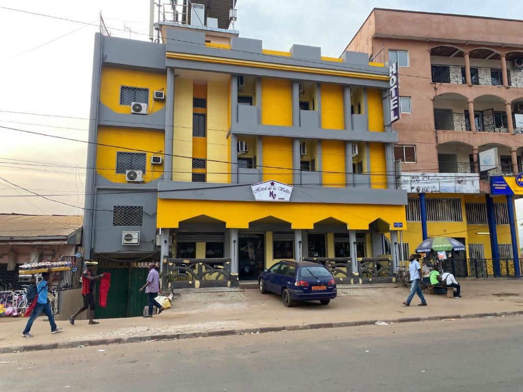 a yellow building with people walking in front of it at HOTEL DE LA VALLEE NEW in Yaoundé