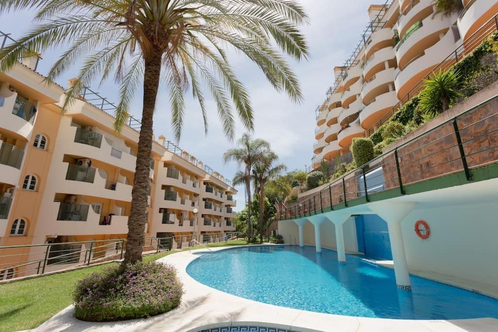 una piscina frente a un edificio con palmeras en Modern apartment with terrace, en Marbella